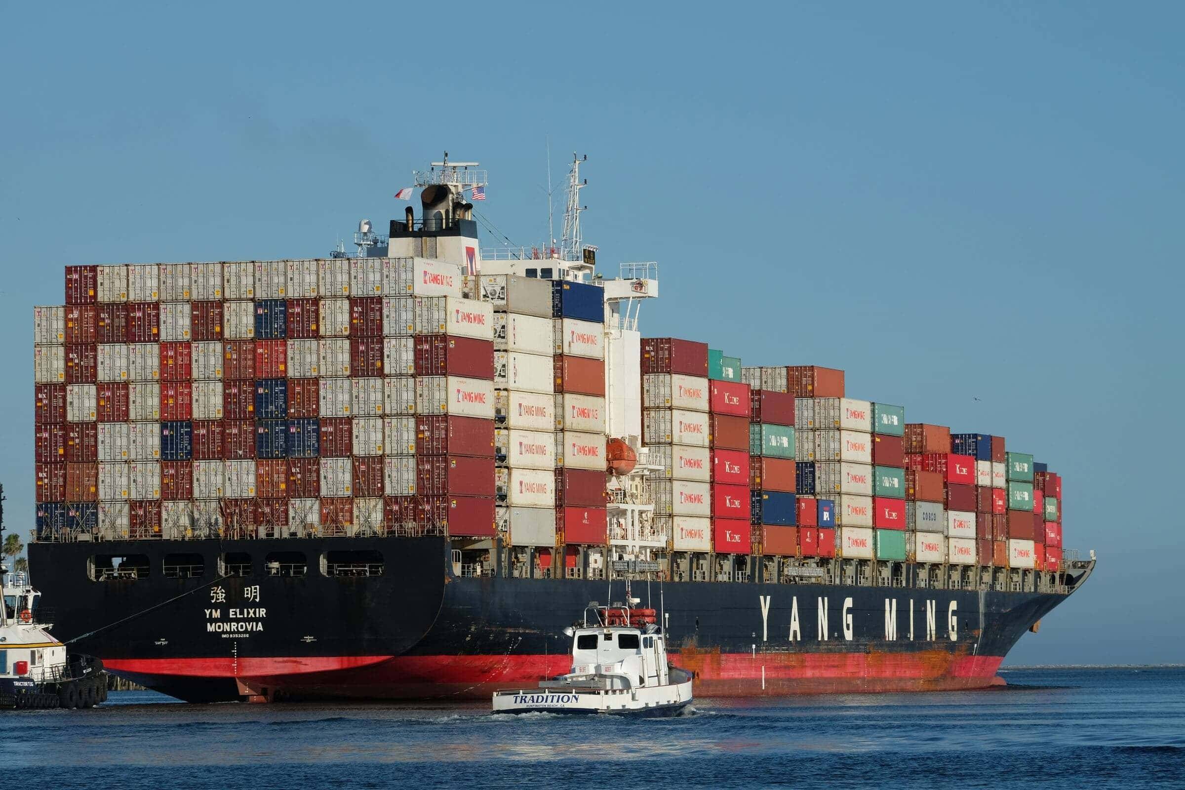 Container ship escorted by tugboats into harbor